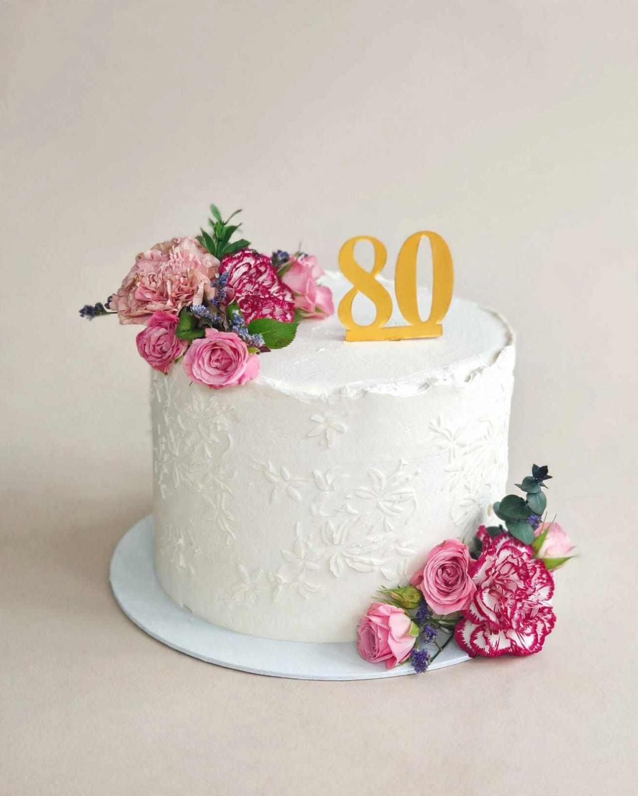 White textured 80th birthday cake with fresh carnations and roses