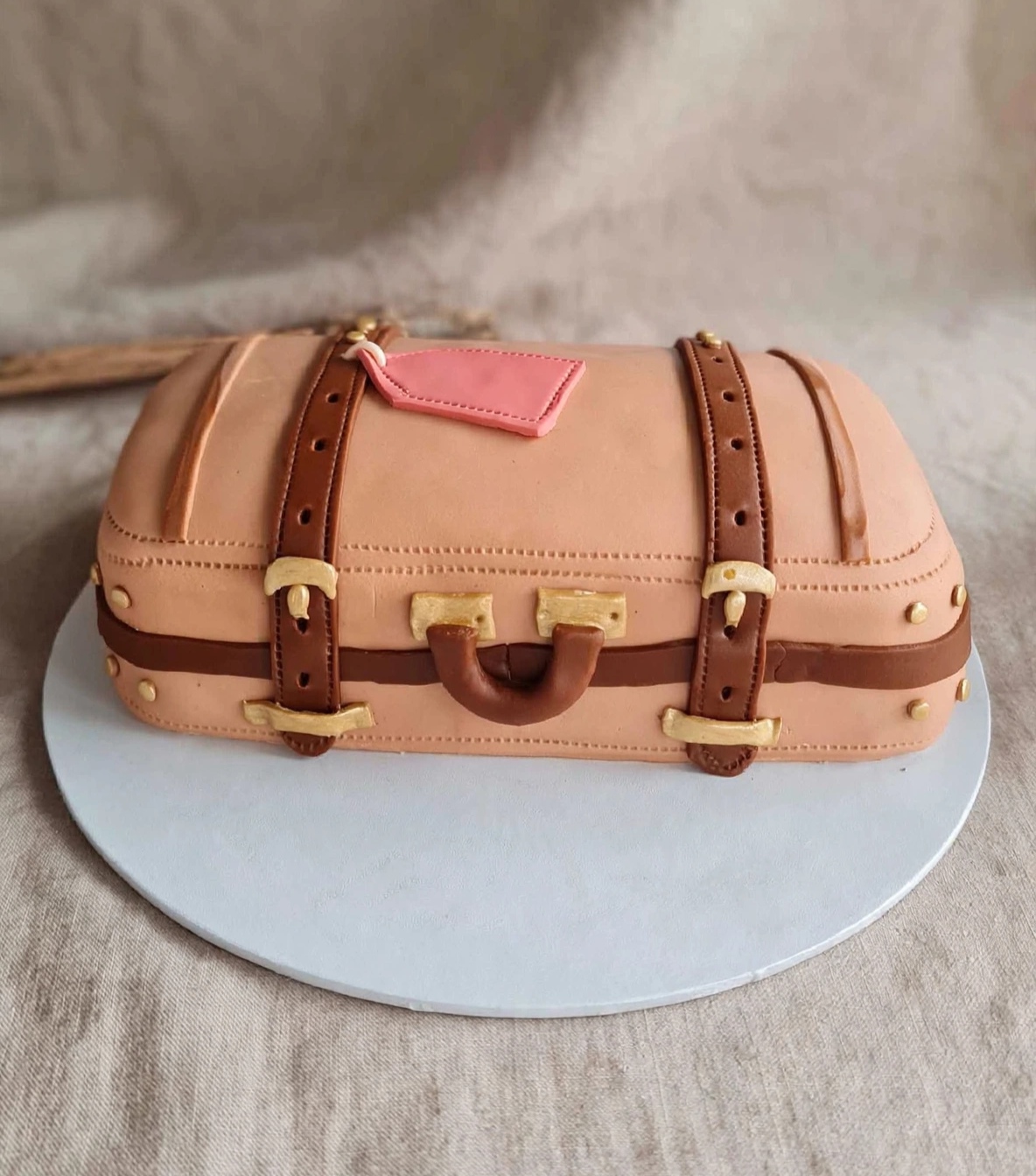Sculpted vintage suitcase cake with fondant straps, buckles and a luggage tag
