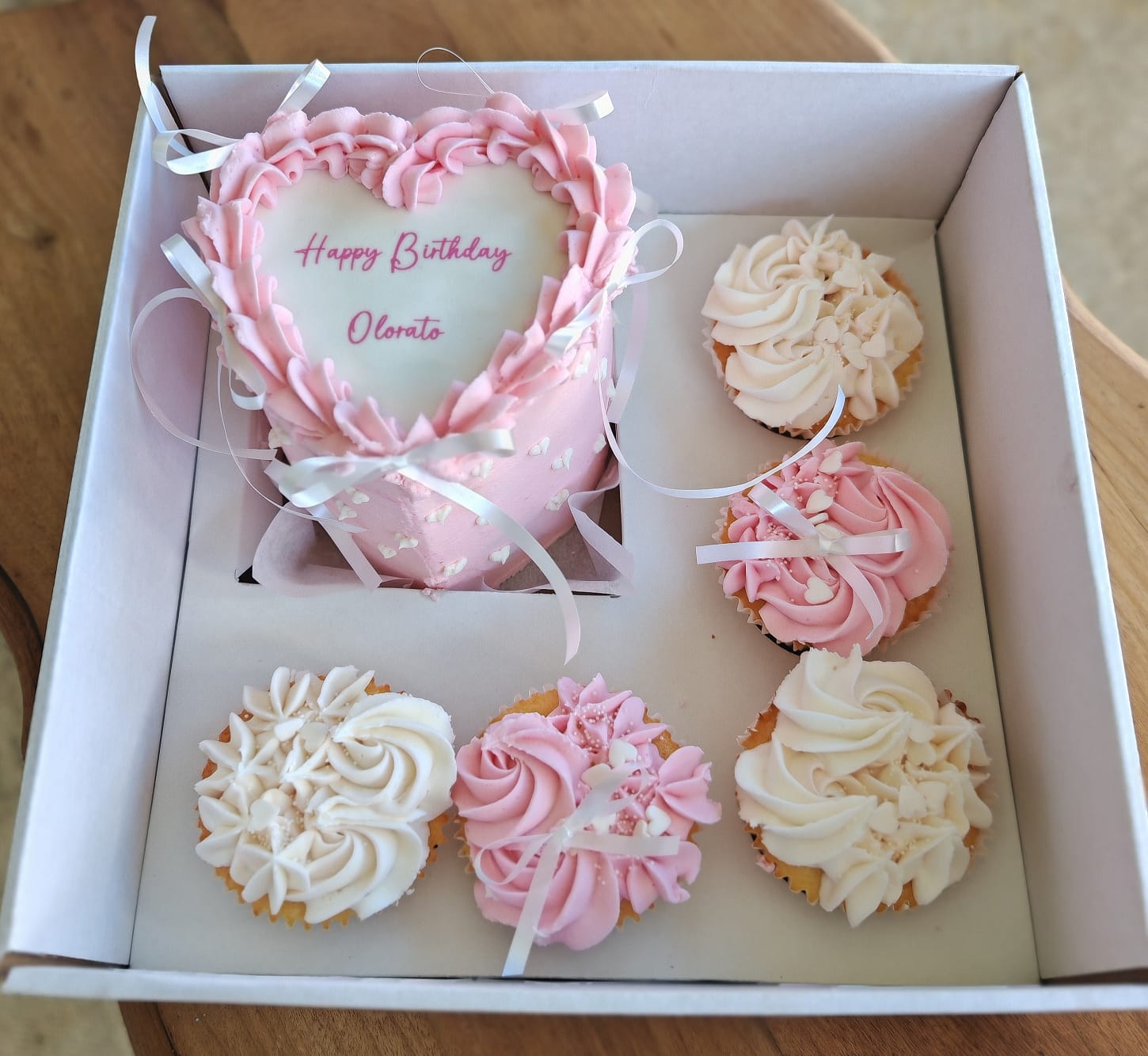 Pink heart-shaped birthday cake boxed with matching cupcakes